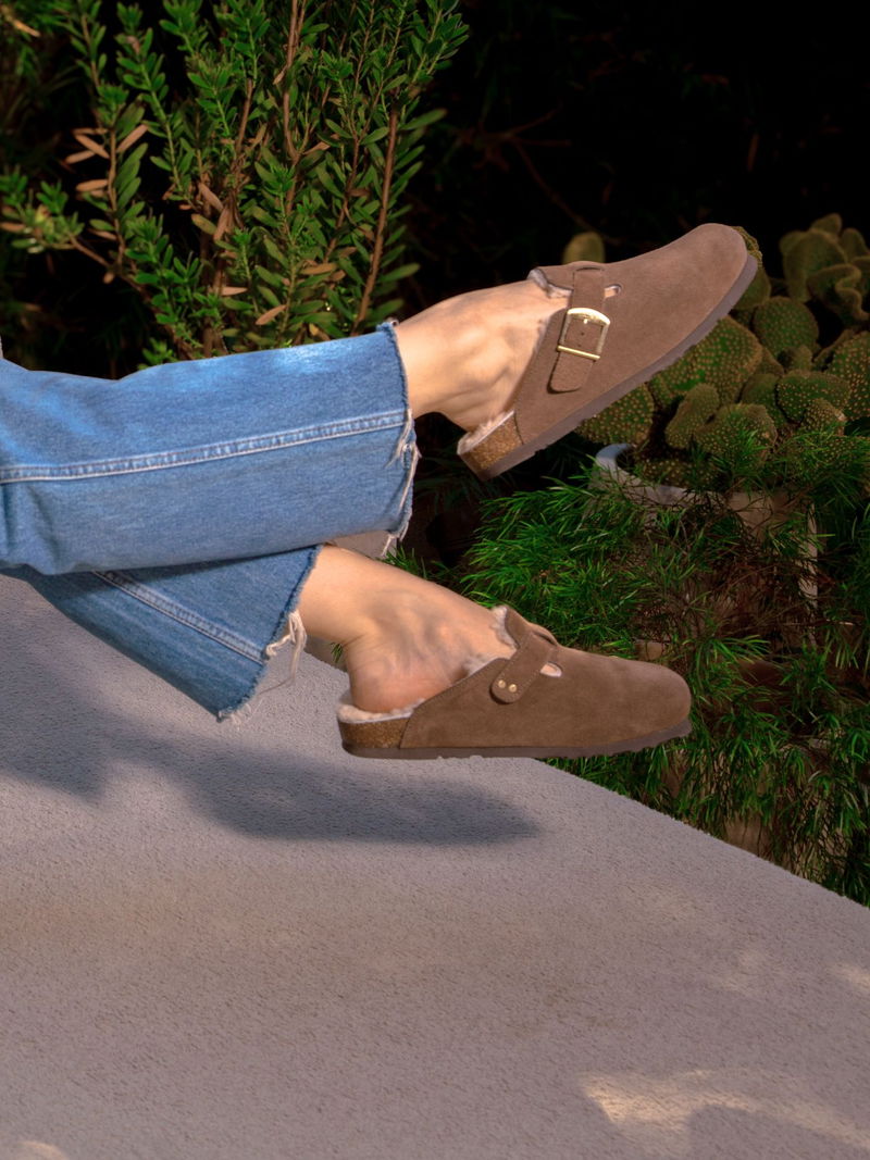 Buty wsuwane typu clogs z miękkiego zamszu z boczną klamrą. Wygodna wkładka z owczej skóry i formowana podeszwa.